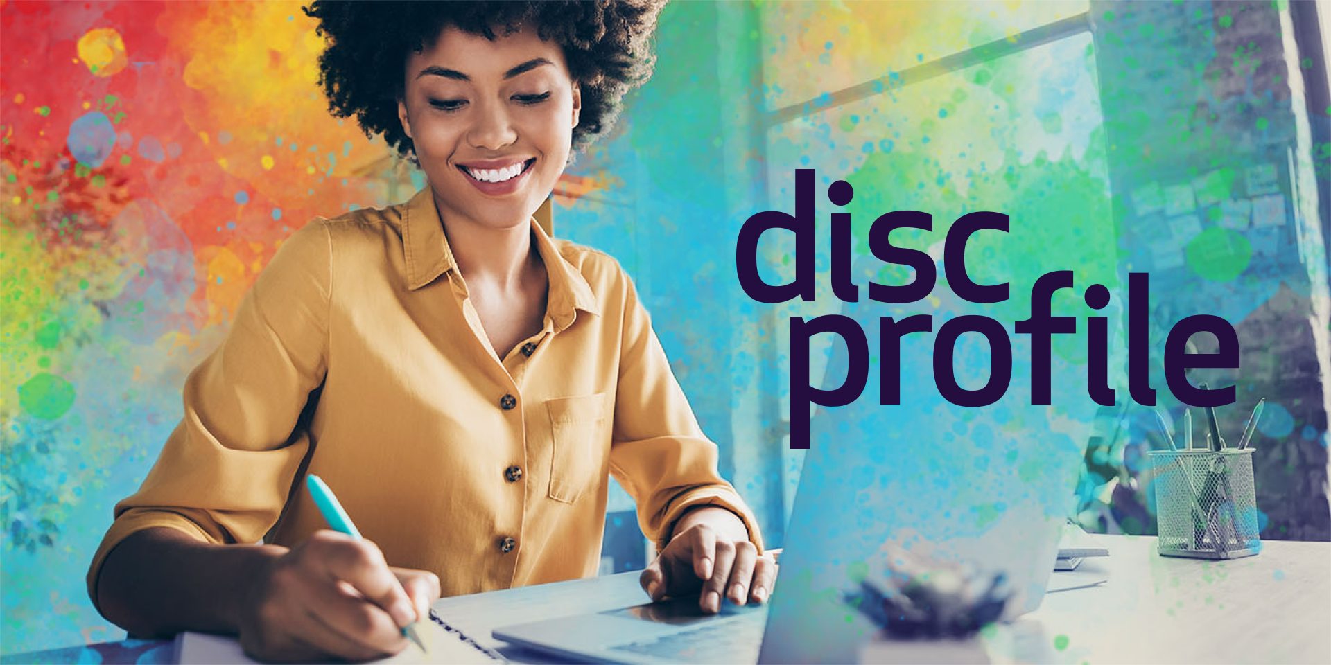 A smiling woman in a mustard shirt writing in a notebook at her laptop, framed by bright watercolor splashes, beside the DiSCProfile logo in plum.